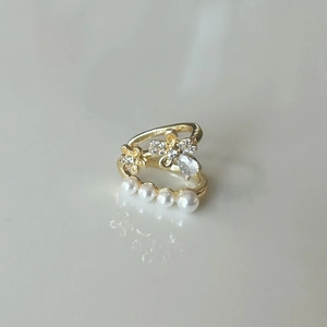 Détail de bague florale dorée ornée de zircons cubiques et perles blanches