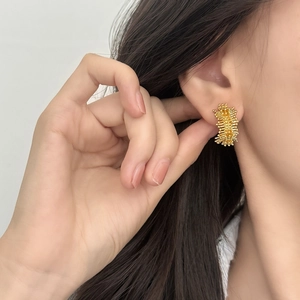 Boucles d'oreilles luxe françaises forme C dorées irrégulières soleil sur un mannequin