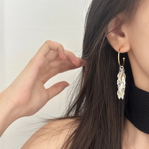 Silver leaf tassel drop earrings with golden circular ring on elegant model's ear