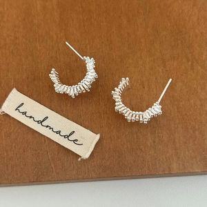 Vue détaillée de boucles d'oreilles argentées en forme de C avec motif texturé