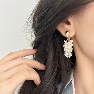 Boucles d'oreilles vintage fleurs blanches avec pompons et accents dorés sur mannequin