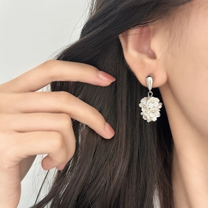 Gros plan sur des boucles d'oreilles fleurs avec pétales en résine sur le mannequin