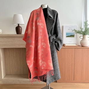 Coral orange paisley pleated scarf with tassels styled on a long wool overcoat