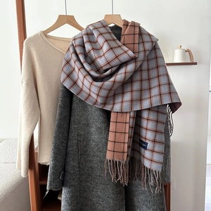 Blue and orange plaid tassel scarf styled with a grey wool coat and cream knit sweater