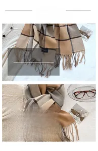 Detail of soft winter scarf with classic plaid pattern and fringed edges in camel tones