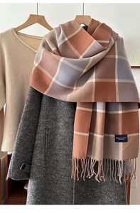 Detailed close-up of plaid winter scarf texture with fringe and woven logo label
