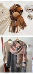 Detail of warm orange and pink plaid winter scarves with fringe and elegant labels