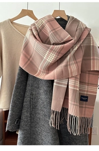 Detail of plaid scarf featuring soft pink and brown checkered patterns with long tassels