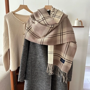 Sciarpa a quadri beige con frange sopra un cappotto di lana per la moda autunno-inverno