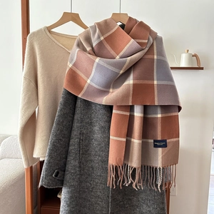 Modern plaid scarf in brick red and lilac with fringe on a wooden hanger with coat