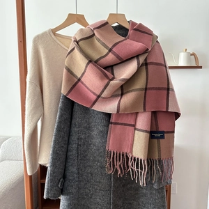 Classic plaid winter scarf with pink and brown tassels on a coat hanger setup