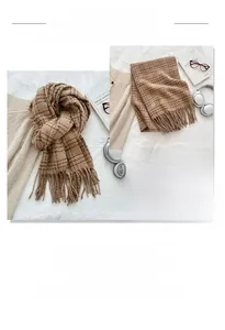 Detail of brown plaid knit scarf with tassels shown in a cozy home setting lifestyle