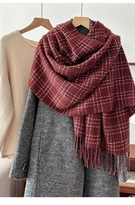 Close-up of red plaid scarf with fringe tassels on winter coat for textured layering