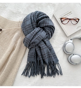 Close-up of blue-grey plaid winter scarf with fringe detail and soft wool texture