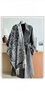 Detail of paisley pattern jacquard scarf with fringe on a grey wool coat mannequin