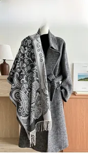 Detail of paisley jacquard shawl with handmade fringe worn over a dark grey coat