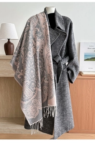 Detail of grey-pink paisley pashmina shawl with tassels on a long wool coat display