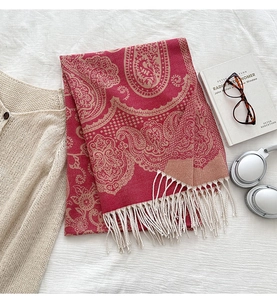 Macro shot of red paisley shawl featuring white fringe details and soft texture