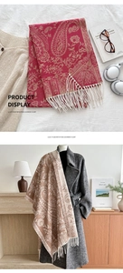 Detail of red and beige paisley shawl with fringe trim on an indoor clothing model
