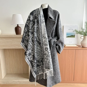 Bohemian paisley scarf with white tassels styled over a long gray wool coat for women