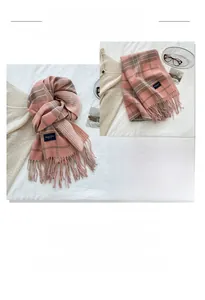Close-up of pink and grey plaid scarf featuring soft tassels and woven elegance label