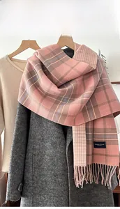 Close-up of pink plaid knit scarf with tassels and Elegant & Classic label on wool coat