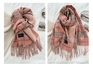 Detail of pink and beige plaid scarf showing soft knit texture and fringe tassels