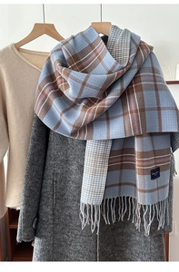 Detail of thick plaid knit scarf with tassels hanging on a hanger for autumn/winter style