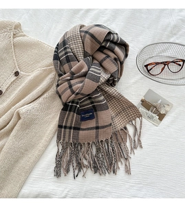 Close-up of thick winter scarf with plaid pattern, houndstooth weave and tassel fringe