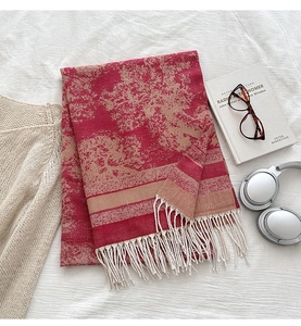 Dettaglio del motivo jacquard rosso e beige su sciarpa morbida effetto cashmere con frange