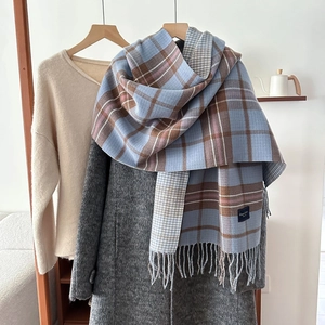Thick plaid knit scarf with fringes and blue label in pastel blue and beige tones