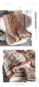 Close-up of caramel paisley jacquard pattern and thick fringe texture on the warm shawl