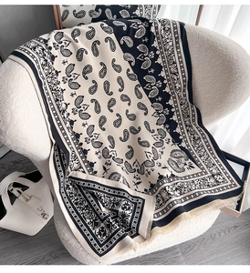 Detailansicht eines beige-schwarzen Schals mit Paisley-Muster und Fransenstruktur