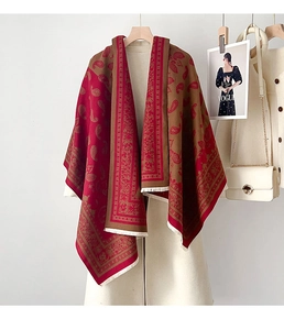 Detail eines Paisley-Schals in Rot und Braun mit feinen Fransen auf weißem Wollmantel