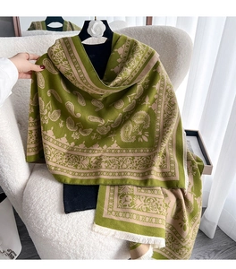 Detail eines grünen Paisley-Jacquard-Schals mit Fransen und weicher Stoffstruktur