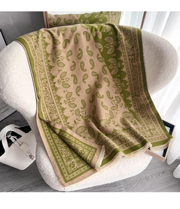Detail eines grünen Paisley-Jacquard-Schals mit kurzen Fransen auf weißem Untergrund