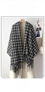 Close-up of thick plaid scarf featuring black and white check patterns and fine fringe trim