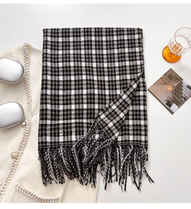 Detailed close-up of classic plaid scarf texture and soft fringe tassels in a flat lay view