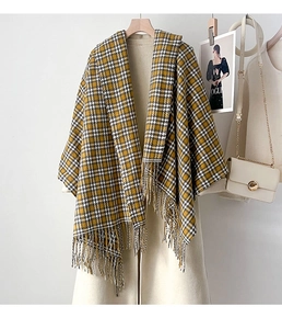 Detail of yellow plaid scarf with thick tassels hanging on a coat for winter fashion