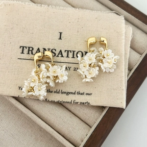 Détails de boucles d'oreilles vintage avec pétales de fleurs blanches et fini doré