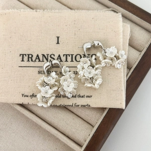 Détail de boucles d'oreilles fleurs blanches élégantes avec perles sur lin rustique
