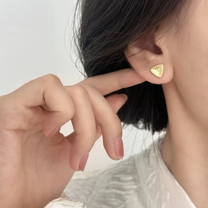Minimalist geometric gold triangle earrings with textured surface worn by a model