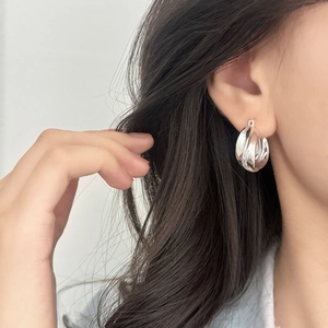 Minimalist silver geometric twist hoop earrings for women shown on a model