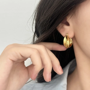 Elegant gold geometric twist earrings with metallic luster on model side profile view