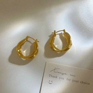 Macro view of gold twisted hoop earrings showing sleek geometric texture and glossy finish