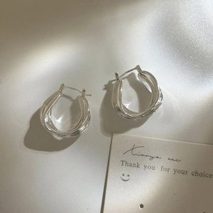 Detailed view of silver twisted hoop earrings with a textured cross design and pin clasp