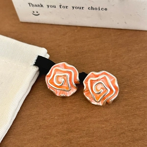 Macro detail of orange enamel rose stud earrings with silver metal petal edges