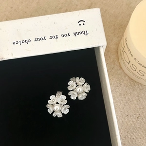 Gros plan de boucles d'oreilles fleurs et perles sur velours noir dans un coffret