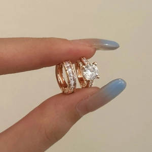 Elegant rose gold earrings set with cubic zirconia stones shown held by hand