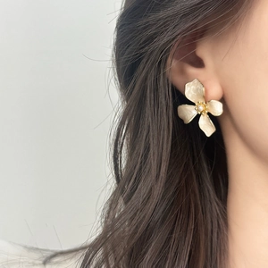 Elegant vintage cream floral earrings with gold details worn by a model in profile